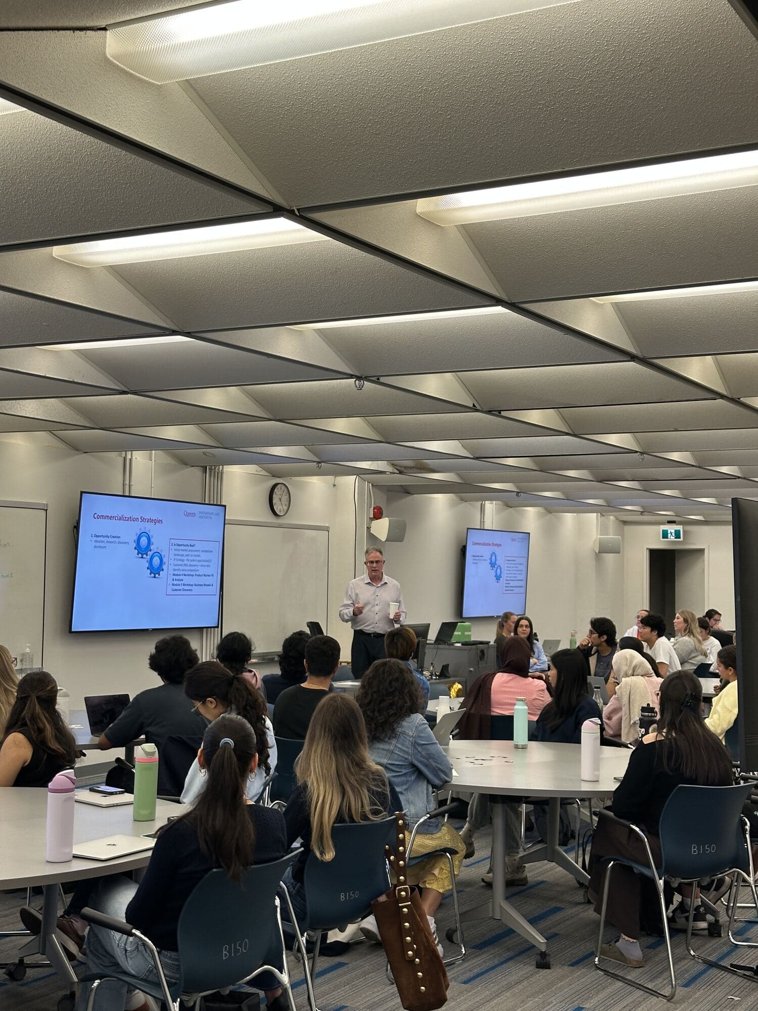 A guest speaker presenting Commercialization Strategies to a full room of students at QUBIC Workshop 01
